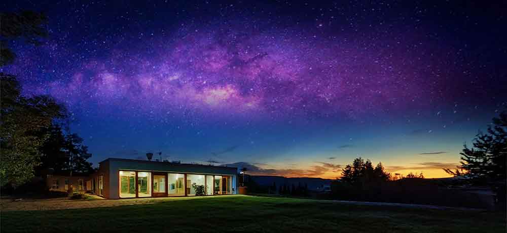 Casa en el campo de noche con vista de la via lactea.